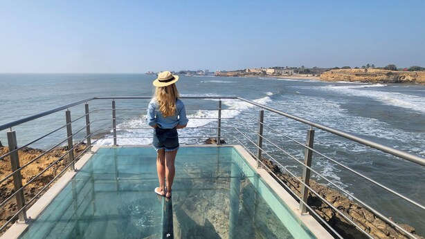 A person standing on a glass-bottomed platform overlooking the ocean. - Ginger Diu Jalandhar Beach (Diu)