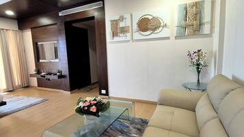 Un salón moderno con una mesa de centro de vidrio, sofá color beige y una obra de arte en la pared.