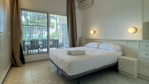 Ein Hotelzimmer mit einem Bett, einem Nachttisch, einer Kommode und einer Klimaanlage.