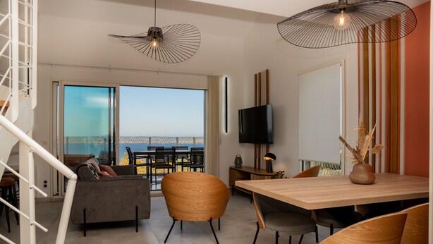 Ein modernes Wohnzimmer mit Balkon, Essbereich und Fernseher.