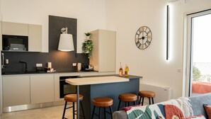 Eine moderne Küche mit Kochinsel, Barhocker und einer Essecke mit einer Couch.