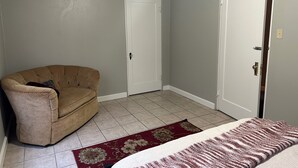 A room with a beige armchair, a red and white rug, and a white door. - Spacious 4-Bdrm house in Ruston with WiFi and AC & Wonderful front & back porch (Ruston)