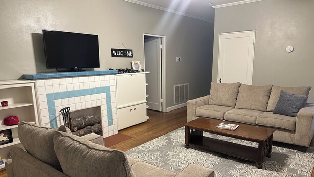 A living room with a TV, sofa, coffee table, and fireplace. - Spacious 4-Bdrm house in Ruston with WiFi and AC & Wonderful front & back porch (Ruston)
