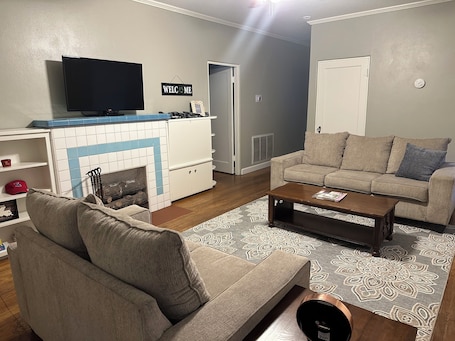 A living room with a TV, sofa, coffee table, and fireplace.