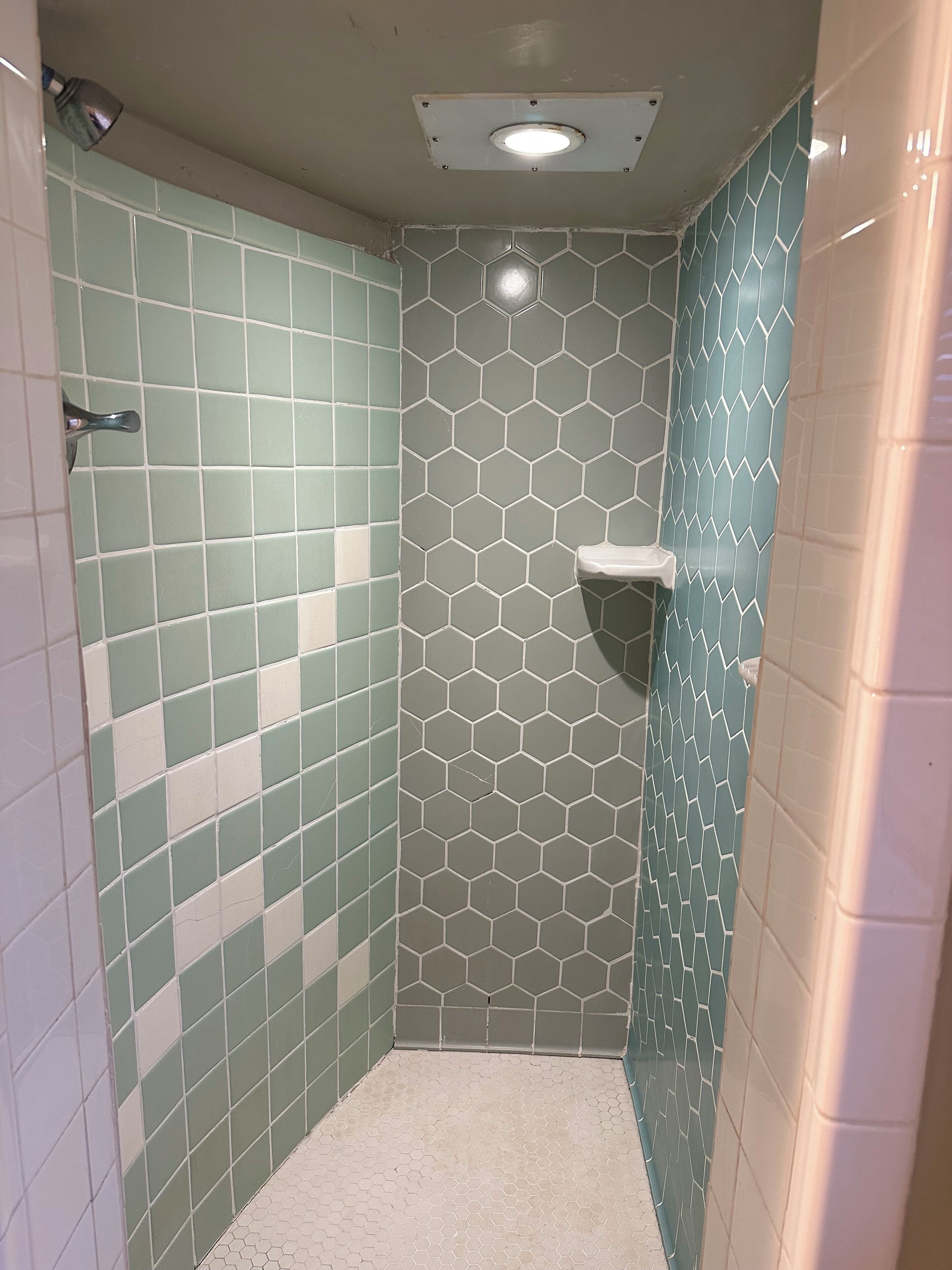 Un petit espace de douche carrelé, avec un motif hexagonal sur les murs et le sol.