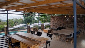 An outdoor dining area with a pool view, wooden ceiling, and brick walls. - Room 1 of 8 Cozy Suites The Hilltop Guesthouse (Harare)