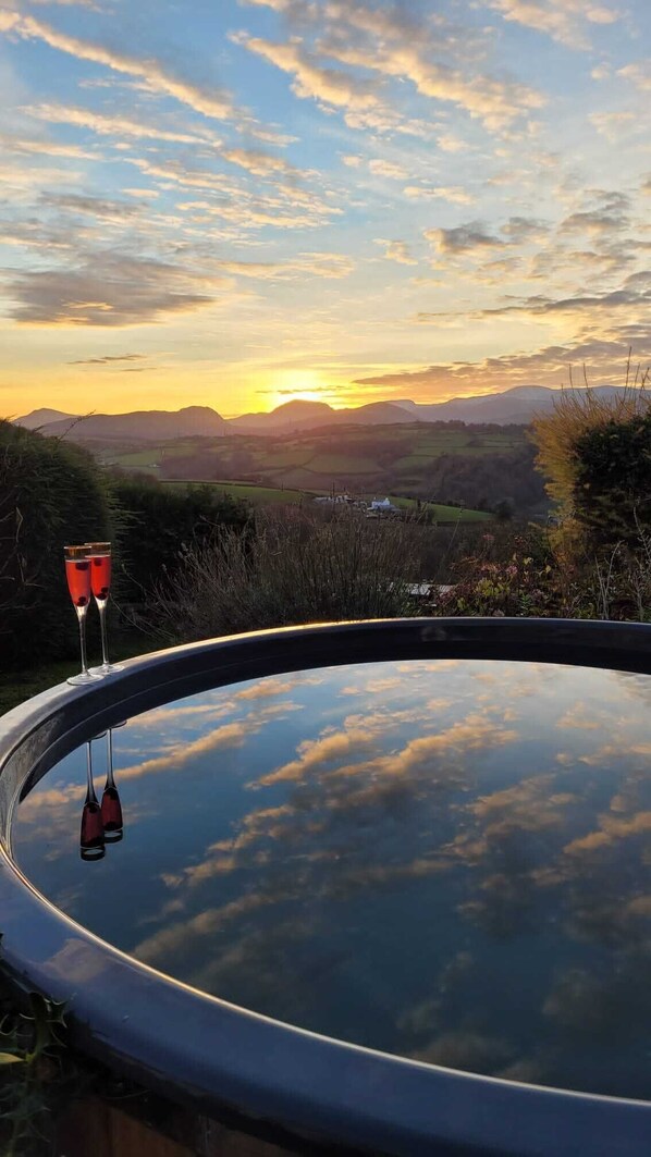 A hot tub with a view of a sunset over a valley.