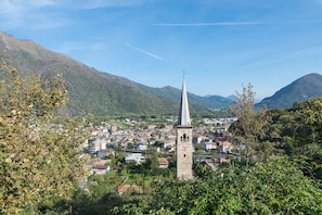 A town with a prominent church tower, surrounded by lush greenery and mountains.