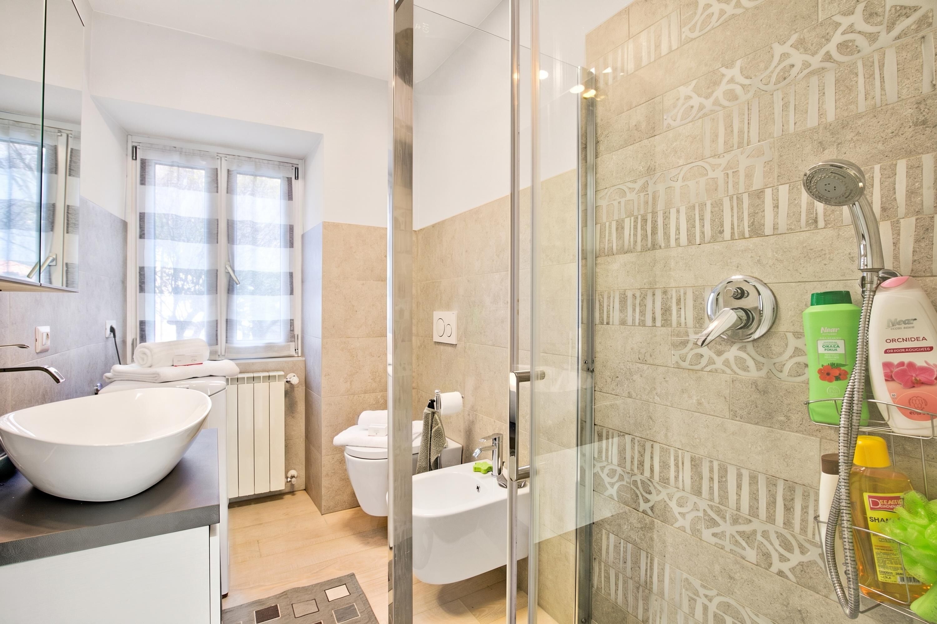 Een moderne badkamer met een douchecabine van glas, een wit wastafelmeubel en een toilet.