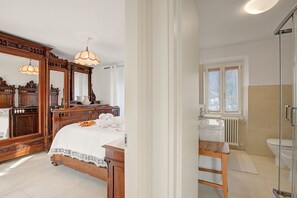 A bedroom with a large wooden bed, a dresser, a mirror, and a bathroom with a sink and toilet.