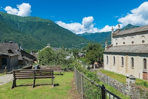 A traditional building with a stone facade, a wooden bench, and a stone pathway leading to it.