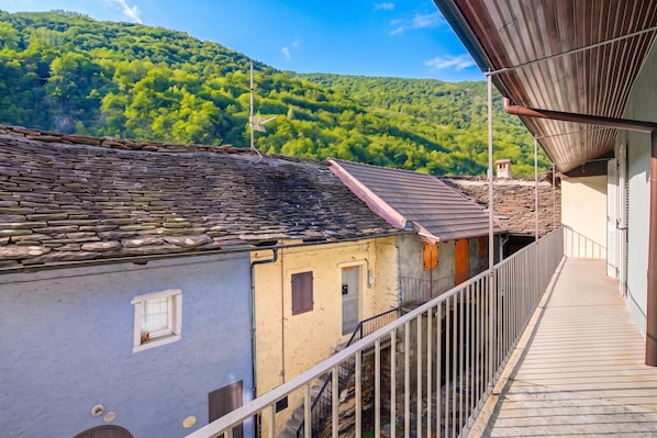 A traditional stone building with a balcony overlooking a forested hillside. - Ornavasso Apartments (Ornavasso)