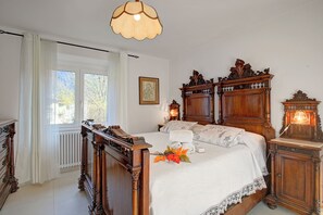 A traditional bedroom with a wooden bed, a nightstand, a dresser, and a window with curtains. - Ornavasso Apartments (Ornavasso)