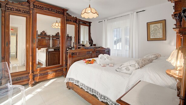 A bedroom with a large bed, wooden furniture, and a mirror. - Ornavasso Apartments (Ornavasso)