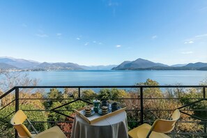 A terrace with a table set for tea, overlooking a lake and mountains.