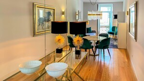 Un espace repas moderne avec une table en verre, deux bols blancs, des chaises vertes et un lustre.