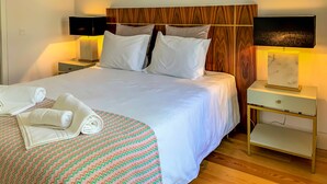 Un lit bien fait, avec du linge de lit blanc, deux tables de chevet avec des lampes, une tête de lit en bois et un tapis à motifs.