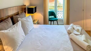 Une chambre d’hôtel avec un lit, des oreillers, une table de chevet avec une lampe, une chaise et une vue sur le balcon extérieur.