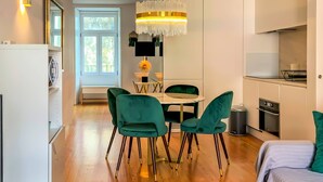 Une cuisine moderne avec un coin repas, comprenant une table ronde, des chaises vertes et un lustre.