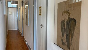 Un couloir doté d’un plancher en bois, de murs blancs et de portes portant des numéros d’identification.