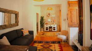 Ein Wohnzimmer mit einer Couch, einem Sessel, einem Fernseher und einem Teppich mit Muster.