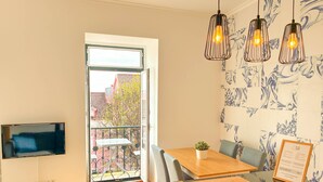 A dining area with a table, chairs, a small plant, and a menu stand. - Charming 2 Bedroom Apartment w/ River View (Lisboa)