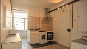 Cocina compacta con lavadora, horno y una pequeña encimera.