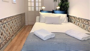 A neatly made bed with striped bedding, a white door, and a plant on the wall. - Apartment w/ Balcony in Príncipe Real (Lisboa)