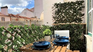 A wooden table set with blue plates and glasses, surrounded by greenery and a white wall. - Apartment w/ Balcony in Príncipe Real (Lisboa)