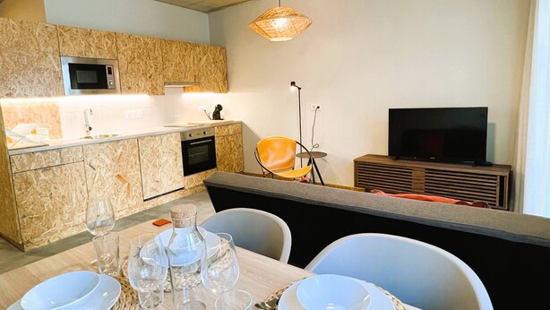 Une cuisine moderne équipée d’un four à micro-ondes, d’un four traditionnel et d’un coin repas avec une table dressée pour deux personnes.