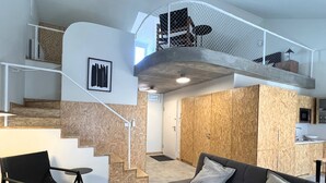 A modern interior with a staircase leading to a loft area, a sofa, and a dining area. - NEW Top Modern Loft w/ AC & River View (Lisboa)