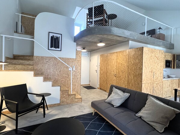 A modern interior with a staircase leading to a loft area, a sofa, and a dining area.