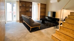 A modern living room with a sofa, a flat-screen TV, and a staircase. - NEW Top Modern Loft w/ AC & River View (Lisboa)