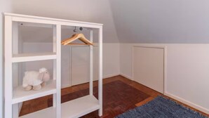 A room with a white shelving unit, a hanging wooden hanger, and a blue patterned rug on a wooden floor. - Spacious Loft w/ City view in Principe Real (Lisboa)