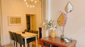 Ein Essbereich mit Holztisch und Stühlen, einer Vase mit Blumen, einem Spiegel und einem Bücherregal.
