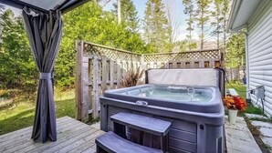 Een jacuzzi met bedieningspaneel, een houten terras en een houten omheining.