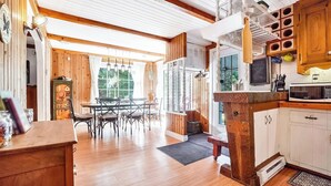 Een houten interieur met een eethoek, keuken en uitzicht door een raam.