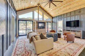 A spacious living room with a high ceiling, large windows, a fireplace, a flat-screen TV, and a cozy seating area. - 5 Mi to Great Sand Dunes NP: Mountain Retreat! (Mosca)