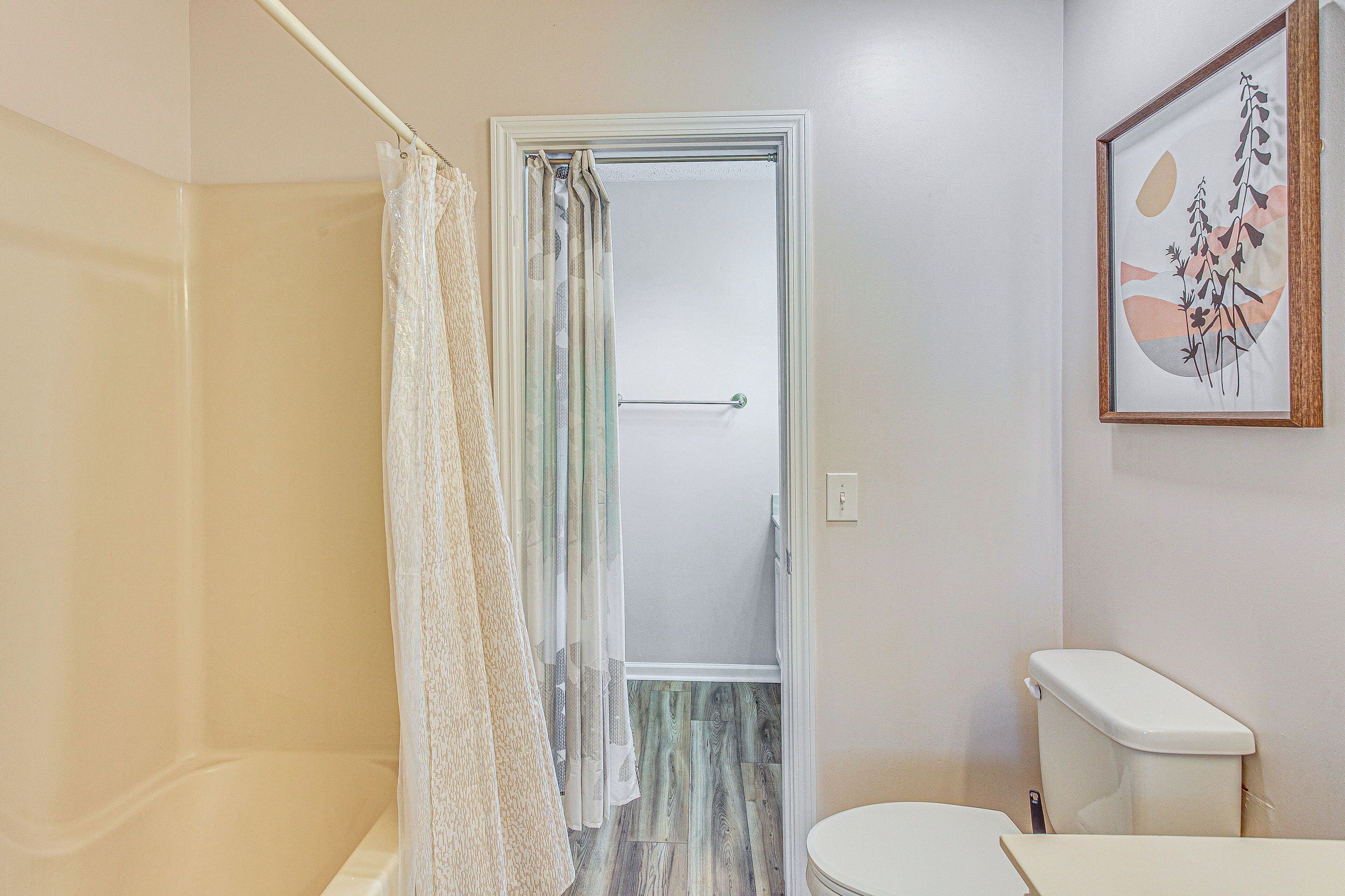Ein Badezimmer mit Dusche, Toilette und einem gerahmten Kunstwerk an der Wand.