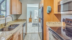 A kitchen with granite countertops, stainless steel appliances, wooden cabinets, and a view to the dining area.