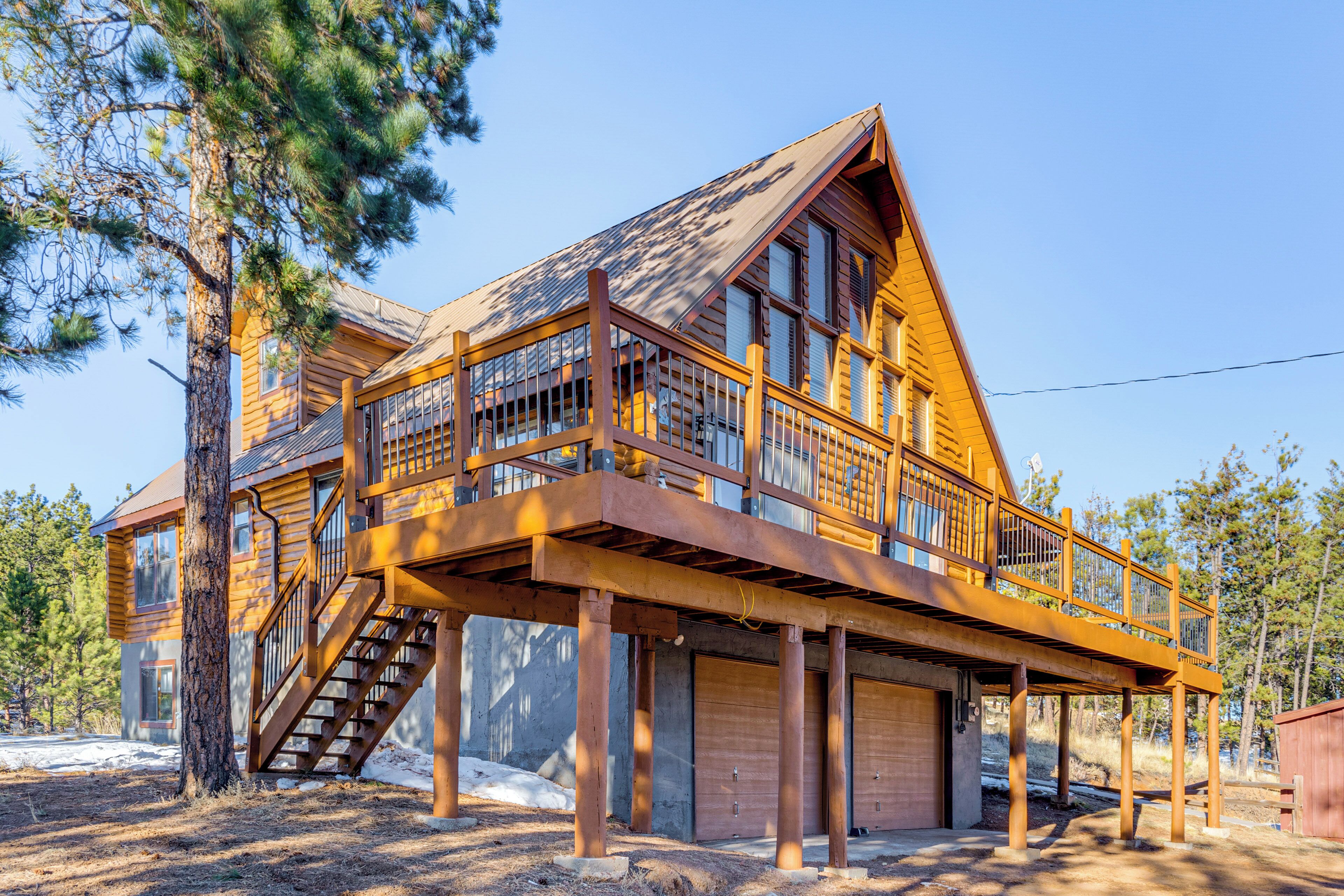 A two-story log cabin with a balcony and a staircase.