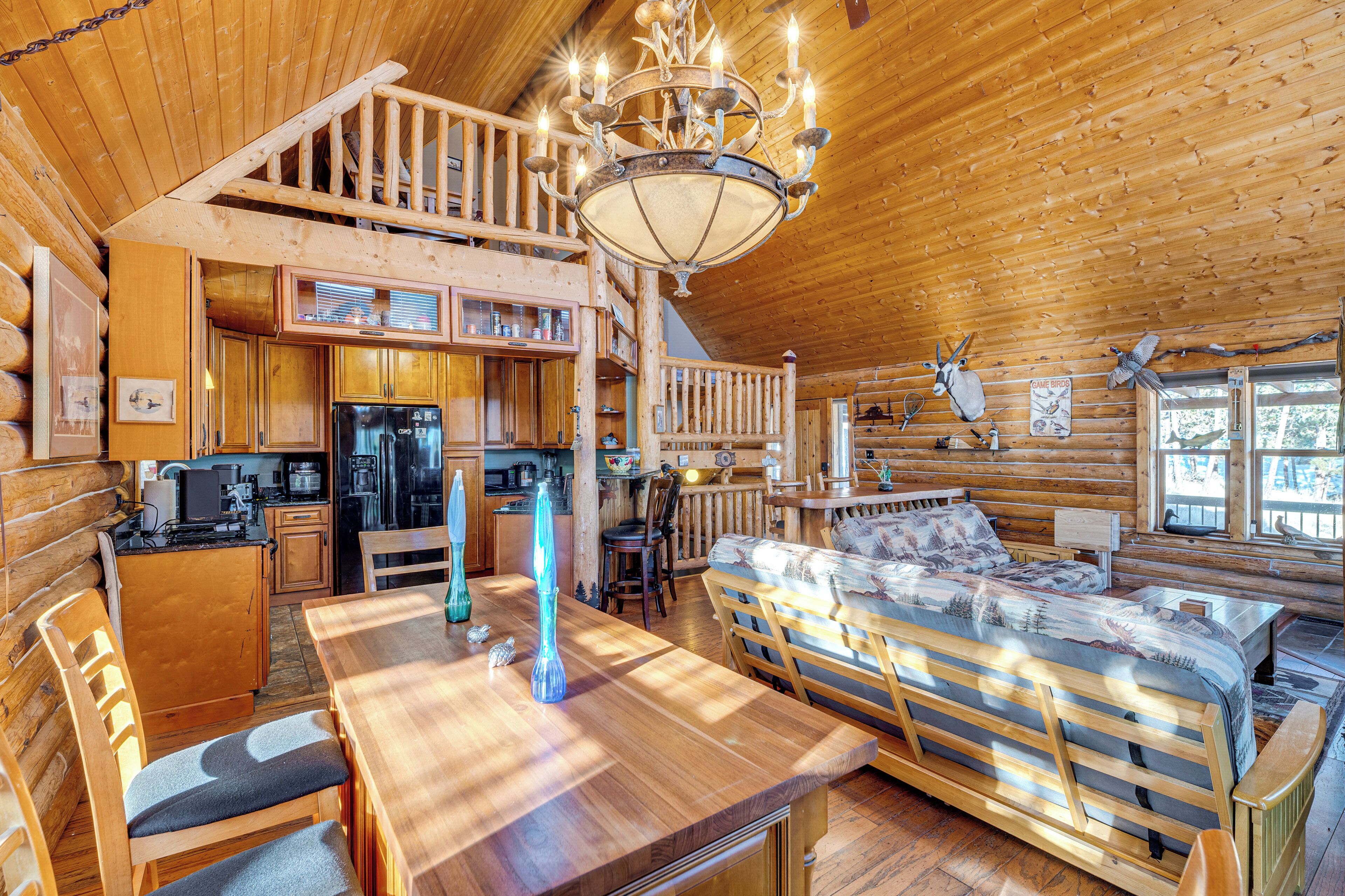 Uma cabana de toras com área de jantar, cozinha e um quarto no mezanino.