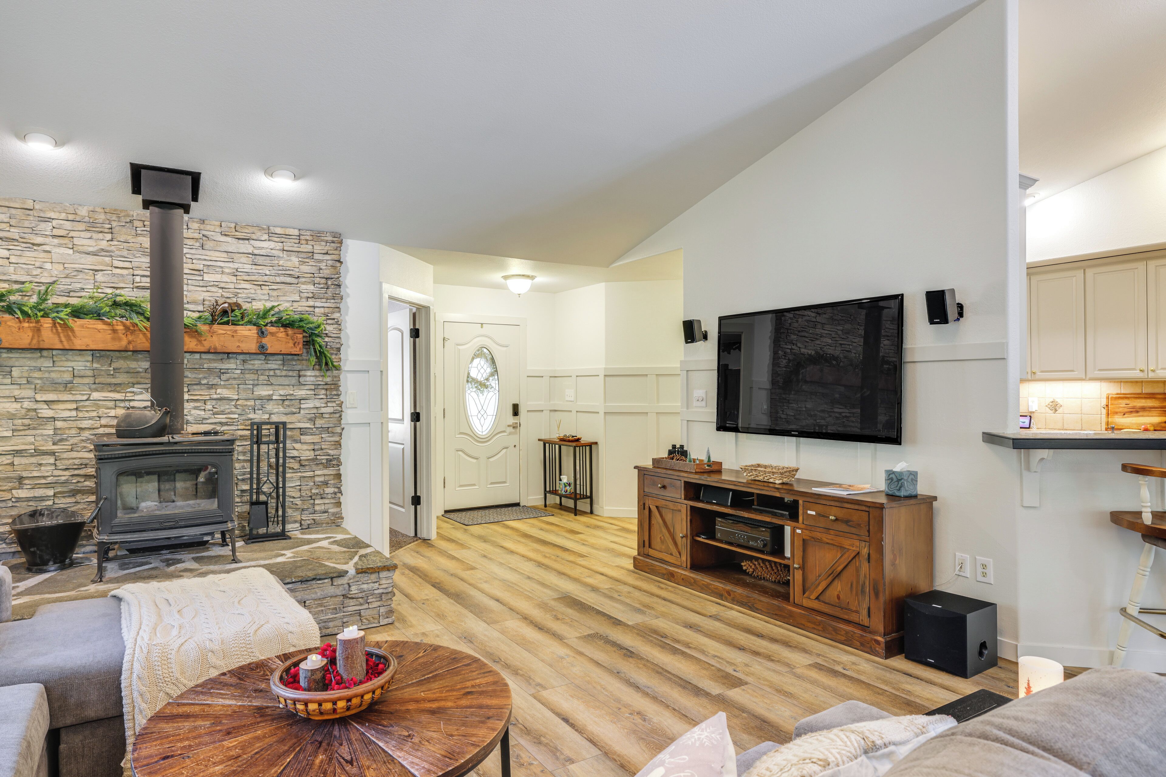 A living room with a stone wall, a fireplace, a TV mounted on the wall, and a wooden entertainment center.