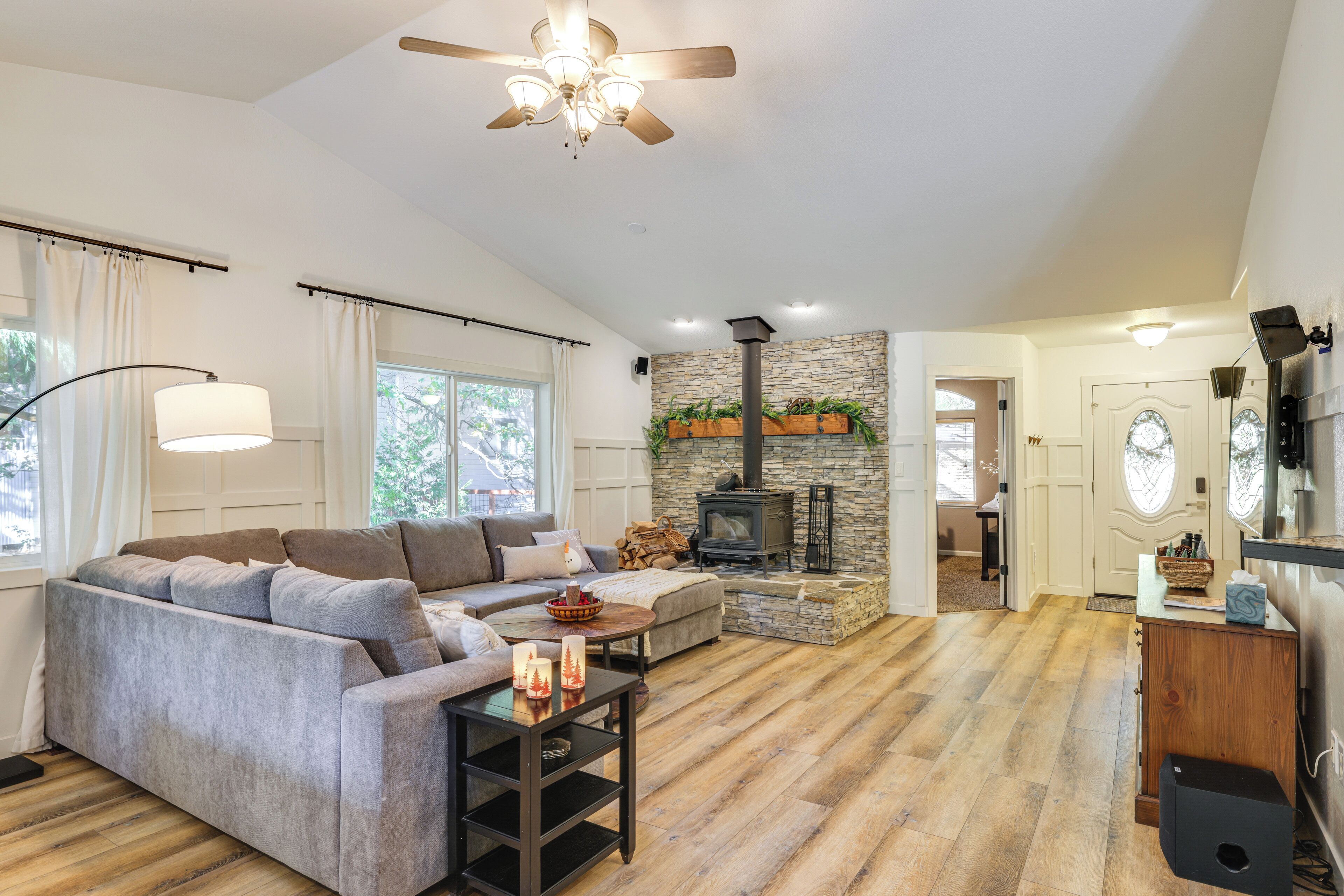 A spacious living room with a stone fireplace, a ceiling fan, and a cozy sofa.