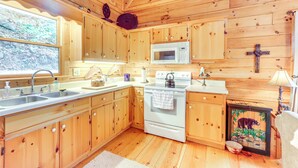 Cocina de cabaña de madera con un lavamanos, estufa, microondas y armarios de madera.