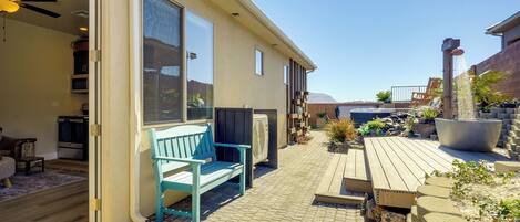 Un espace patio avec une terrasse en bois, un banc bleu et un grand bac à fleurs.