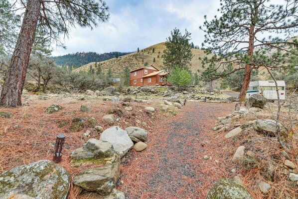 A rustic cabin with a gravel path, surrounded by pine trees and rocks. - Cabin on Little Salmon River ~ 10 Mi to Riggins! (Pollock)