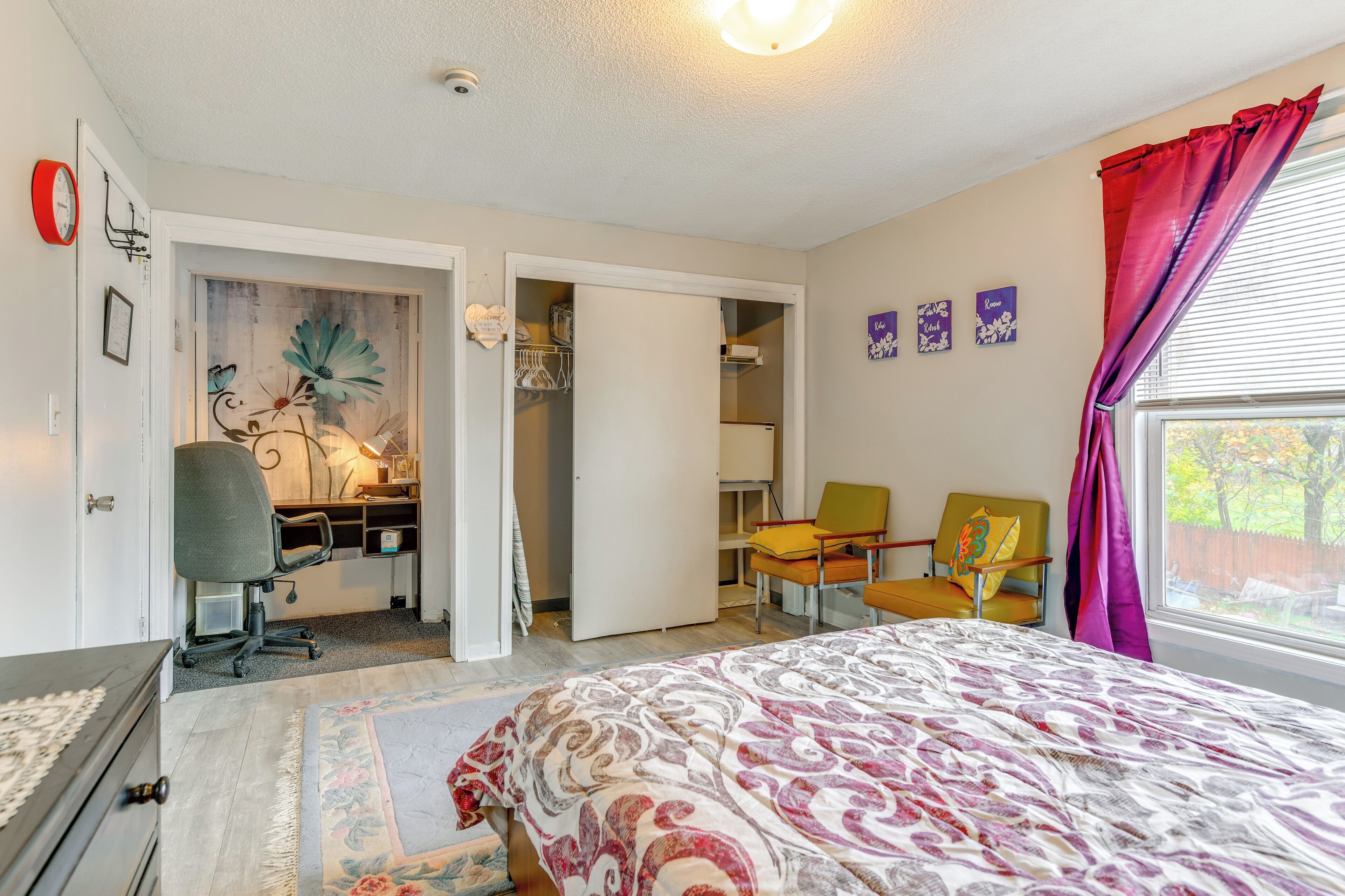 Une chambre à coucher comprenant un lit, un bureau, une chaise, une armoire et une fenêtre avec des rideaux.