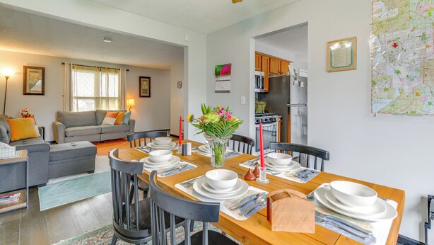 A dining area with a wooden table set for four, surrounded by chairs. There is a kitchen area with cabinets and appliances in the background. - 4 Mi to Dtwn: Family Home in Buffalo (Buffalo)