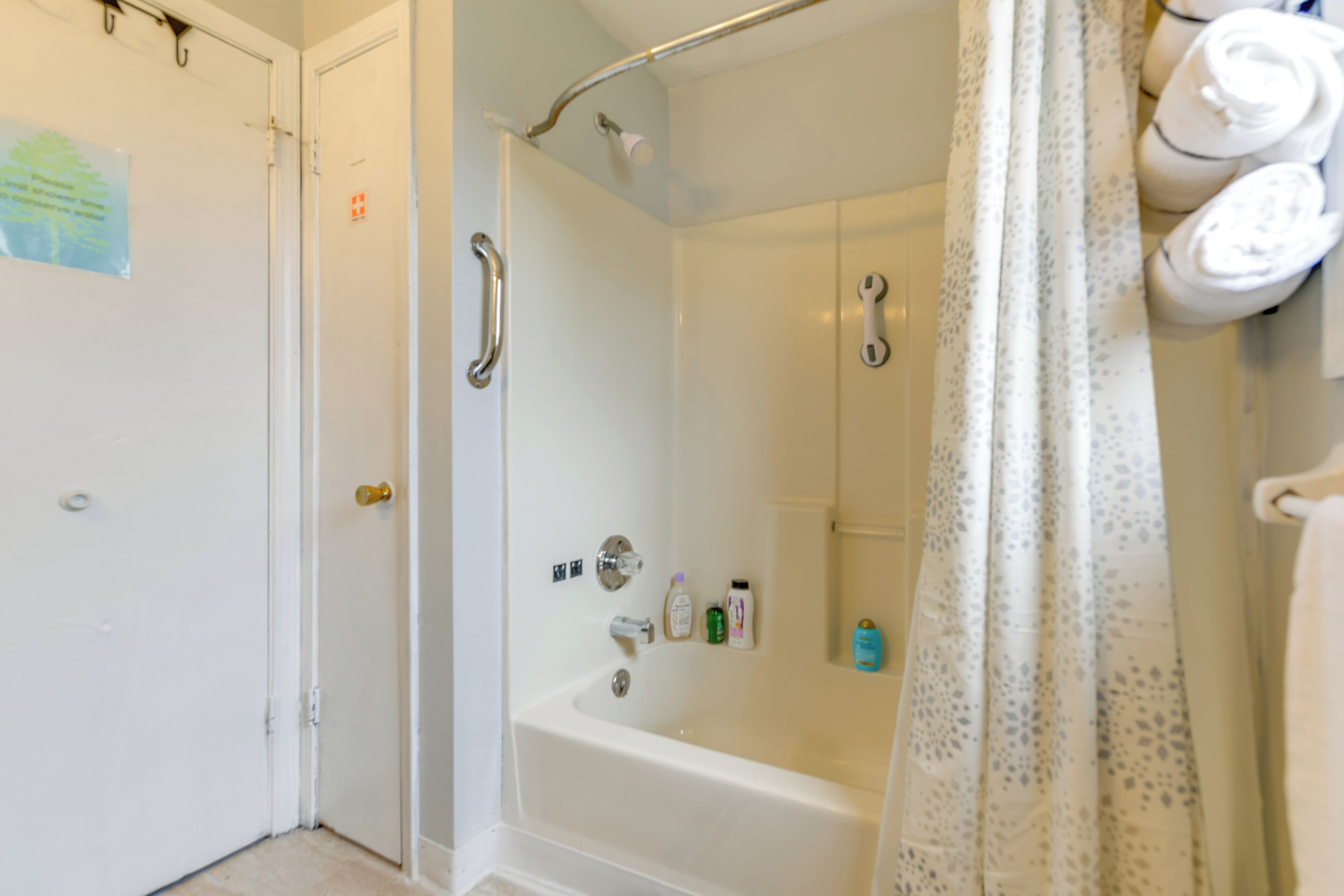 Une salle de bain avec une baignoire, une douche et des toilettes. Des serviettes sont accrochées au mur et il y a un rideau de douche.